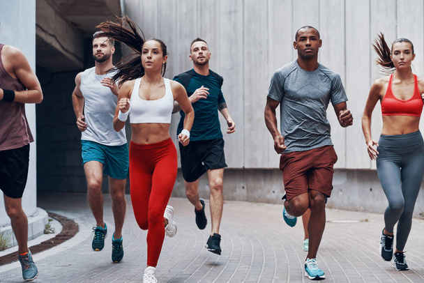 Group of young people in sports clothing running in city street  - Fotoğraf, Görsel