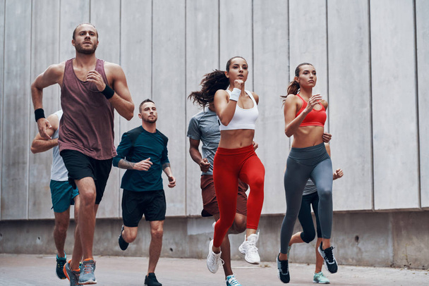 sportive people in sports clothing jogging outdoors at wall - Foto, Bild