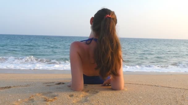 Mladá dívka v plavkách, ležící na mořské pláži a slunění. Krásná Kavkazská žena, která odpočívám na břehu oceánu během letní dovolené. Koncept odpočinku na pobřeží letoviska. Pomalý pohyb zavřít - Záběry, video
