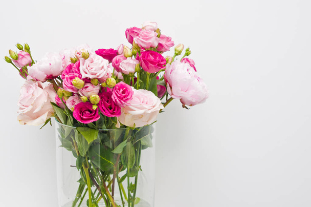 Букет розовых роз, пионерские цветы в стеклянной вазе на полке
 - Фото, изображение