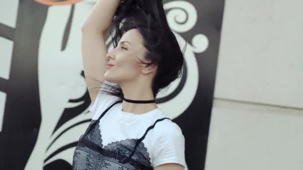 Een jonge vrouw in denim shorts flirtatiously poseren voor de camera pronken met haar lange haren. - Video