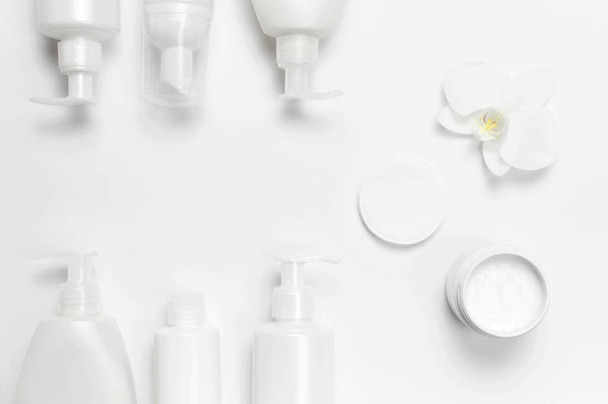 Contenitori di bottiglia cosmetici bianchi e fiori di orchidea su sfondo bianco vista dall'alto posa piatta. Cosmetici SPA branding mock-up, concetto di prodotto di bellezza biologica naturale, stile cosmetico minimalismo
 - Foto, immagini