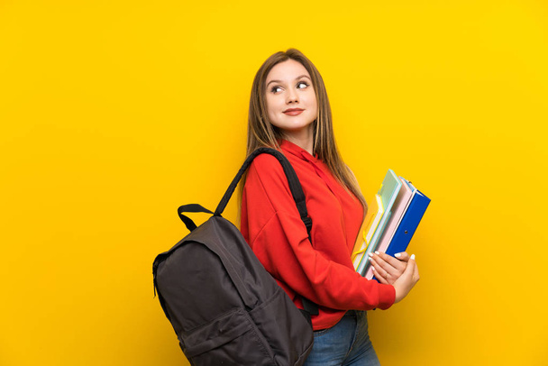 Sarı arka plan gülüyor üzerinde genç öğrenci kız - Fotoğraf, Görsel