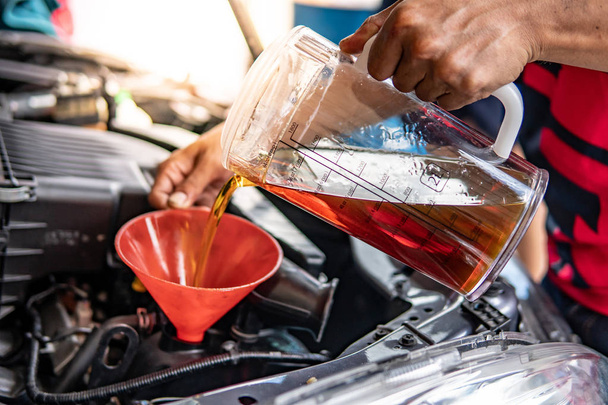 Mécanicien automobile main verser de l'huile dans le moteur de voiture
 - Photo, image