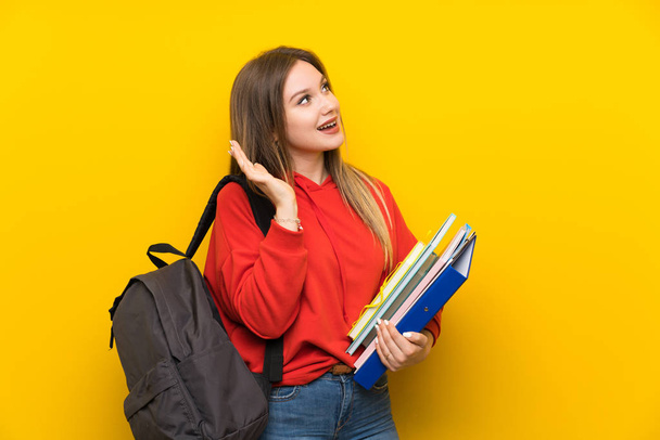 Adolescente estudante menina sobre fundo amarelo com expressão facial surpresa
 - Foto, Imagem