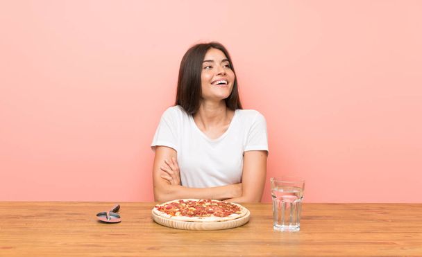 Молода жінка з піцою дивиться вгору, посміхаючись
 - Фото, зображення