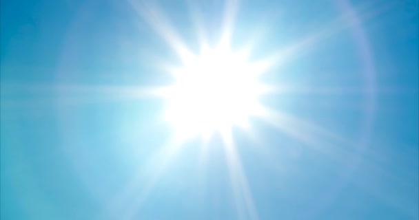 Kijkend naar heldere, levendige zon met zonnestralen en lens flare op blauwe zomer hemel - Video