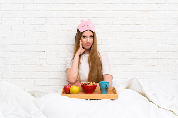 Молодая женщина в халате с завтраком несчастным и разочарованным
 - Фото, изображение