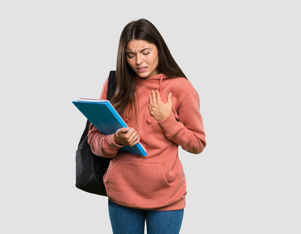 junge Studentin hält Notizbücher mit Herzschmerz vor isoliertem grauen Hintergrund - Foto, Bild