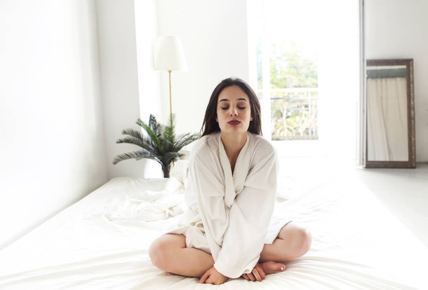 Портрет красивої жінки в білому халаті в спальні
 - Фото, зображення
