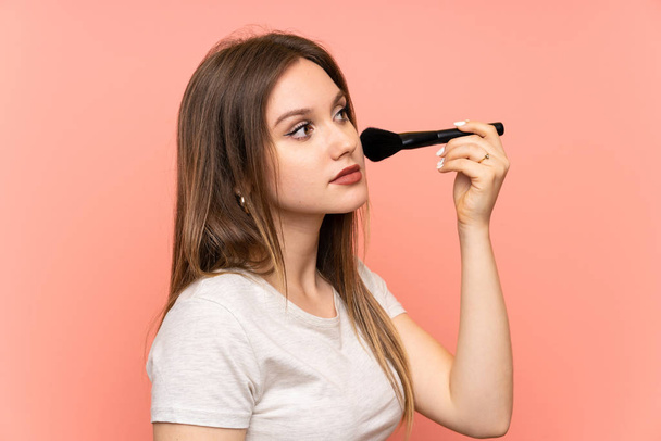 Chica adolescente sobre fondo rosa con cepillo de maquillaje
 - Foto, imagen
