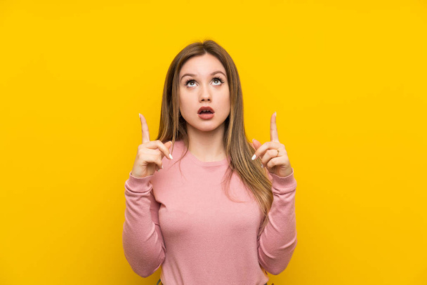 Ragazza adolescente su sfondo giallo isolato che punta con il dito indice una grande idea
 - Foto, immagini