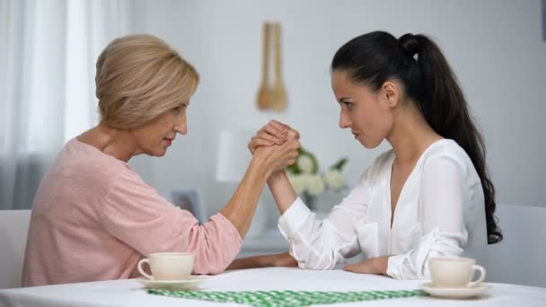 Mother and daughter-in-law looking on each other during arm wrestling battle - Πλάνα, βίντεο