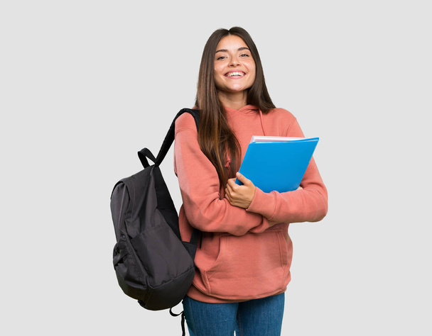 Młoda kobieta uczeń trzyma notebooki z ramionami skrzyżowane i patrząc w przód na białym tle szary - Zdjęcie, obraz