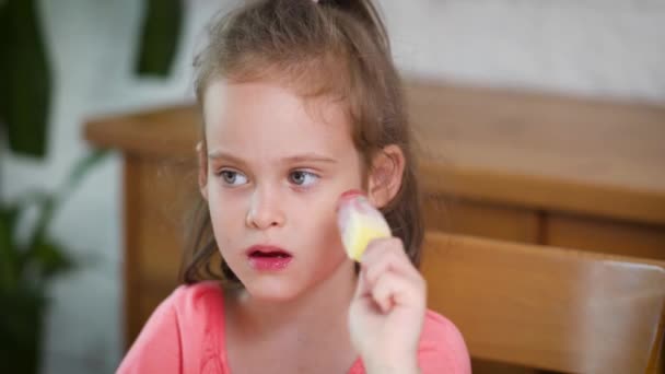 Kaunis pieni tyttö syö herkullista värikästä jäätelöä
 - Materiaali, video