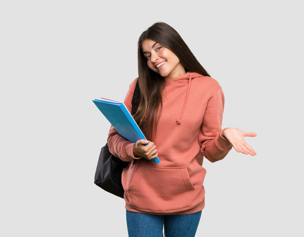 İzole gri arka plan üzerinde gülümseyen deftertutan genç öğrenci kadın - Fotoğraf, Görsel