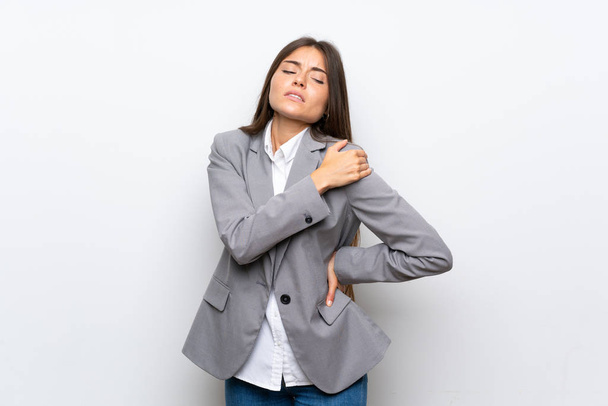 Jonge zakenvrouw over geïsoleerde witte achtergrond die lijden aan pijn in de schouder voor het hebben van een inspanning - Foto, afbeelding