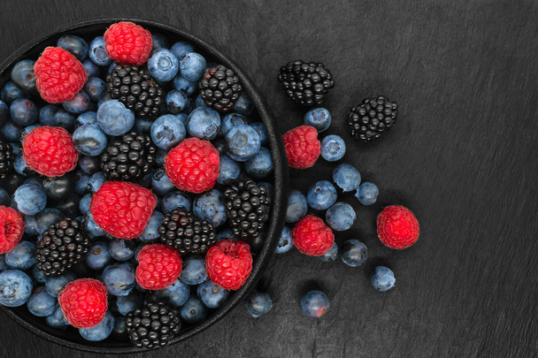 Различные ягоды в круглой и черной чугунной чаше
 - Фото, изображение