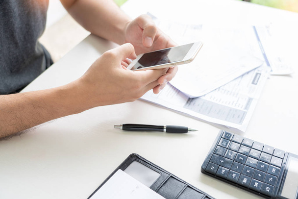 Homem usando calculadora e calcular recibo de contas em despesas domésticas
 - Foto, Imagem