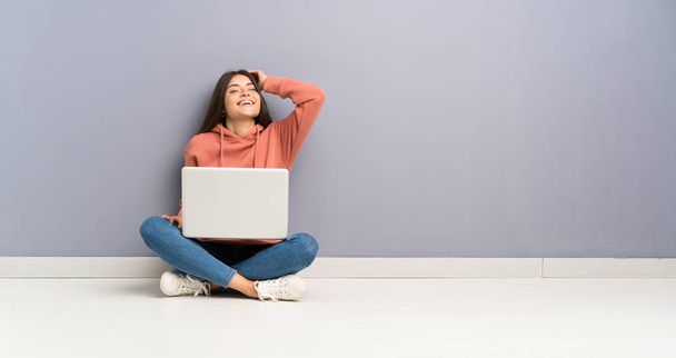 Jeune fille étudiante avec un ordinateur portable sur le sol riant
 - Photo, image