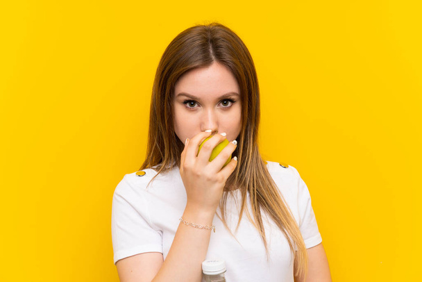Tiener meisje over gele muur met een appel - Foto, afbeelding