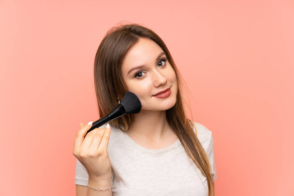 Teenager girl over pink background with makeup brush - Fotografie, Obrázek