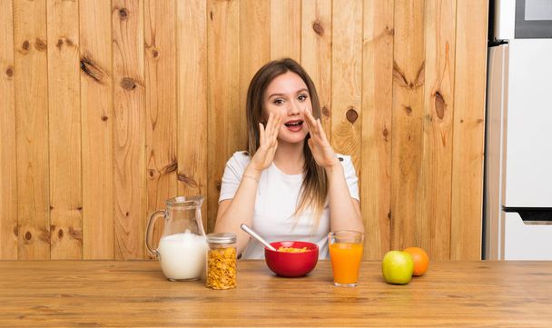 Giovane donna bionda che fa colazione urlando con la bocca spalancata
 - Foto, immagini