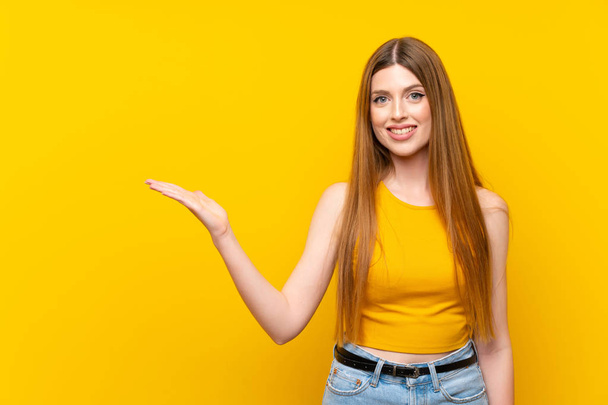 Jonge vrouw over geïsoleerde gele achtergrond houden copyspace denkbeeldig op de Palm - Foto, afbeelding