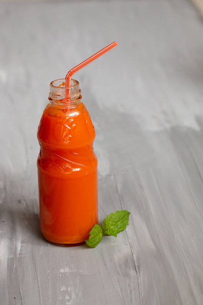 Succo di carota in una bottiglia con foglie di menta su sfondo grigio. Concetto di cibo sano
 - Foto, immagini
