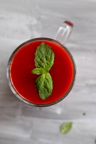 tomato juice in a glass with a mint leaves on grey background, top view. Healthy food concept - Фото, изображение