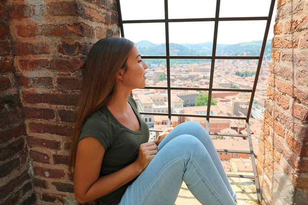 Evropská cestovatelka, která se dívá na Bologni cityni z vrcholu Asinelliho věže, proslulá středověká turistická atrakce v Itálii - Fotografie, Obrázek