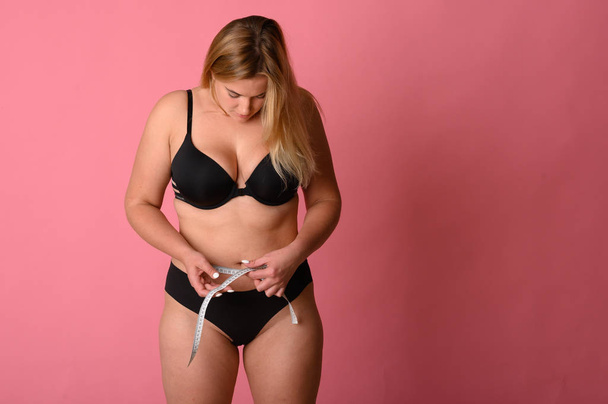 siyah bikini giyen kız bel boyutunu ölçer - Fotoğraf, Görsel