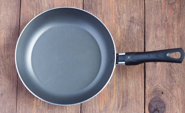 empty frying pan with non-stick coating on wooden background - Photo, Image