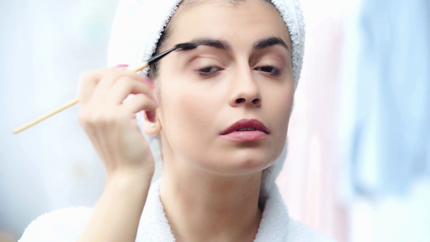 Kobieta w szlafroku Stylizacja brwi z pędzlem kosmetycznym - Materiał filmowy, wideo