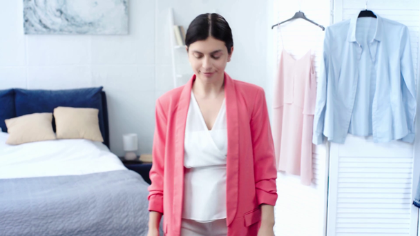 αναστατωμένη γυναίκα προσπαθεί σε ροζ μπλέιζερ, λευκό παντελόνι και μπλούζα στο υπνοδωμάτιο - Πλάνα, βίντεο