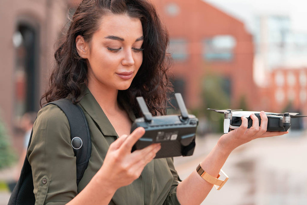 Young beautiful woman launching drone quadcopter at urban background. - Valokuva, kuva