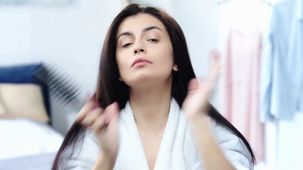 brunette woman brushing healthy long hair with comb - Felvétel, videó