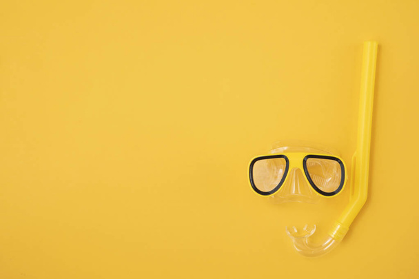 A yellow snorkel and diving mask on a yellow background. overhead lay flat - Фото, изображение
