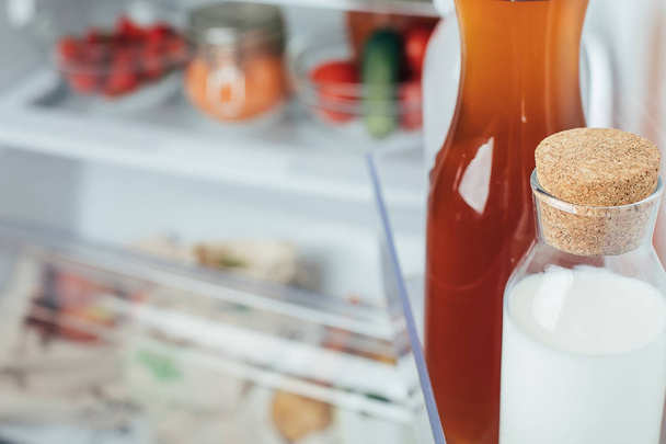 Otevřená chladnička naplněná mléčnou lahví, šťávou a čerstvým ovocem a zeleninou. - Fotografie, Obrázek