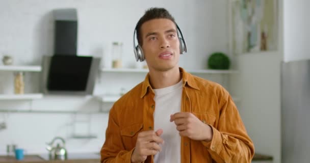 Hispanic man is listening music in wireless headset at home - Filmagem, Vídeo