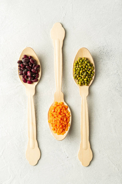 Different kinds of beans in spoons on white background - Photo, Image