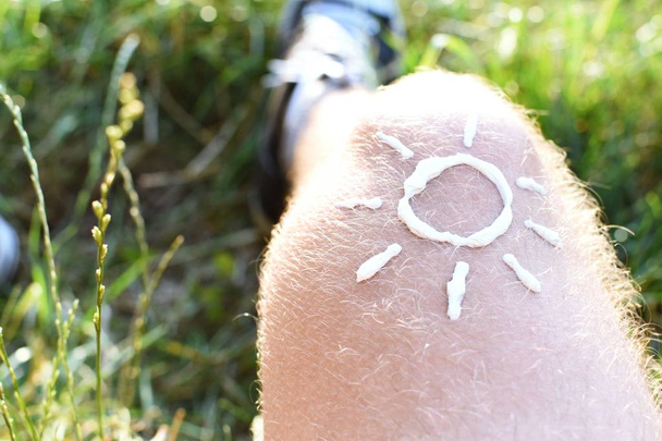 Έννοια για την προστασία από τον ήλιο σε ζεστές μέρες της παραλίας με ένα αρσενικό πόδι με ένα βραχιόλι  - Φωτογραφία, εικόνα