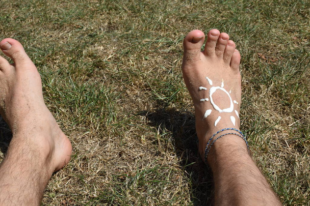 Концепция защиты от солнца в жаркие дни на пляже с мужской ногой с браслетом
  - Фото, изображение