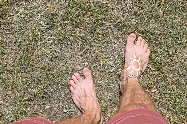 Koncepce ochrany slunce na horkých plážových dnech s mužskou nohou s kotlet  - Fotografie, Obrázek