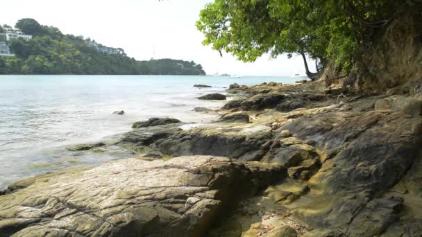 Paisaje de costa en la playa de Ao Yon, olas arrastradas sobre las rocas en ángulo bajo, mar de Andaman con yates bajo cielo azul nublado en phuket, Tailandia
. - Metraje, vídeo