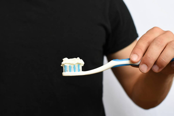 Un uomo tiene uno spazzolino da denti davanti al suo busto, invece di dentifricio è crema sui pennelli concetto astratto per l'igiene dentale e contro il numero zuccherino-pas
 - Foto, immagini