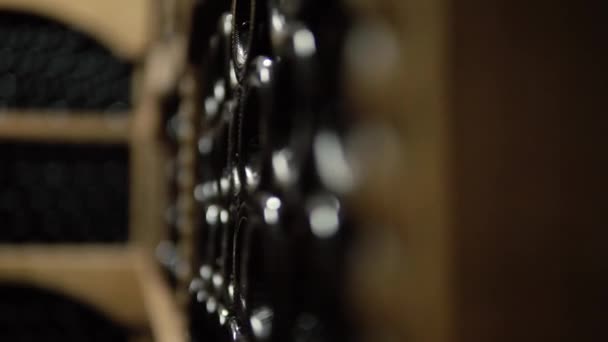 Wijnflessen liggen in stapel in de kelder. Glazen flessen rode wijn opgeslagen in houten planken in stenen kelder. Binnenondergrondse wijnkelder in wijnmakerij - Video