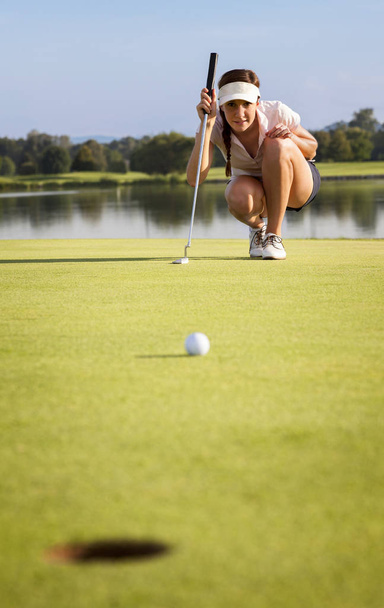 Girl golfer analyzing the green for putting the ball into cup. - Fotografie, Obrázek