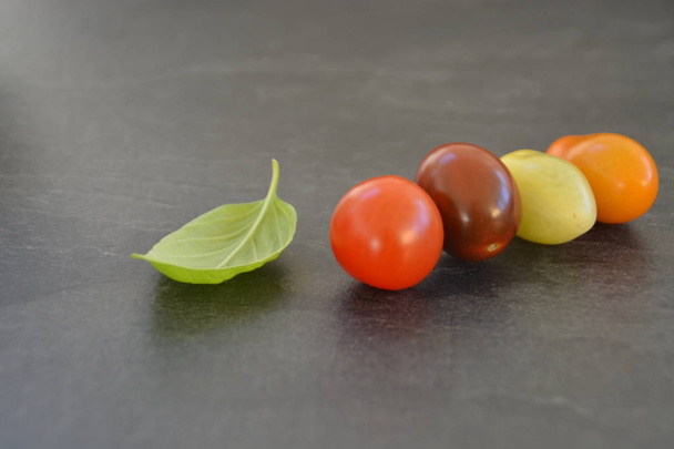 Different types of tomatoes in different colors and basil - concept with fresh and healthy different tomatoes, with space for text for other elements  - Photo, Image