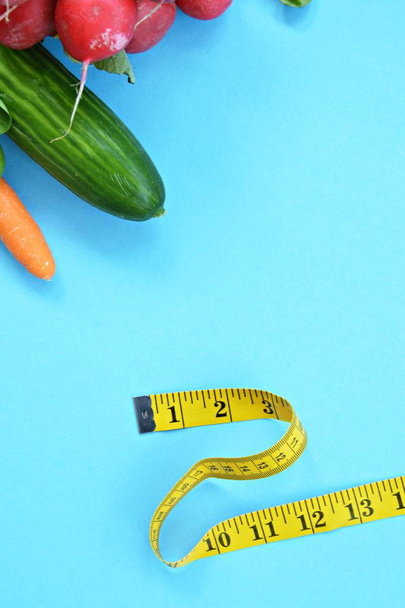 アインファブリゲンベースに横たわる測定テープで包まれた新鮮なカリカリ野菜 - 体重を減らす健康的な食事のためのコンセプト - 写真・画像